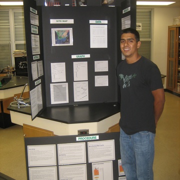 High school intern Sebastian posing in front of his science fair display
